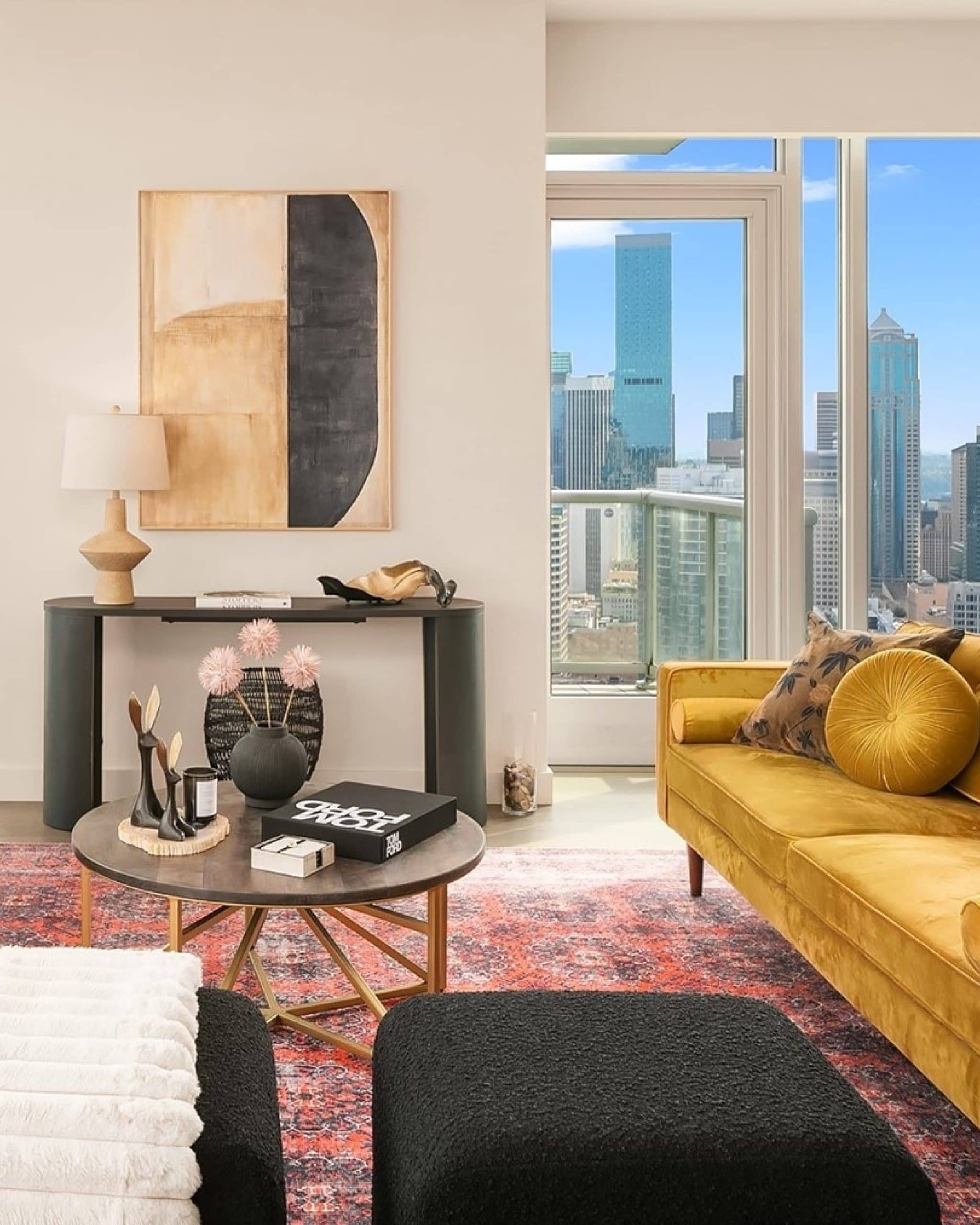 Modern living room with a yellow velvet sofa and coffee table overlooking a sunny Seattle city skyline.